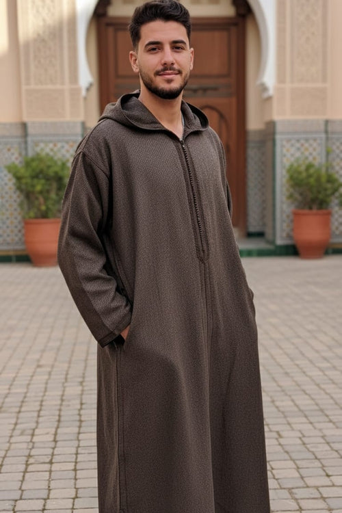Man wearing an olive-brown hooded Moroccan thobe by a mosque doorway