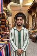 Man wearing a green and cream striped hooded Moroccan thobe in a Fès market