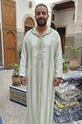 Man wearing an ivory and green striped hooded Moroccan thobe